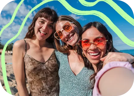Three friends are taking a selfie on a beach.