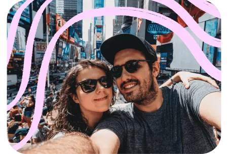 A couple is taking a selfie in the middle of a bustling Times Square.