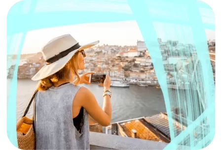 A woman is taking a picture of a riverside city view.