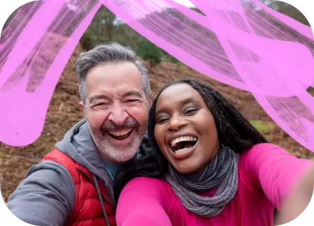An interracial couple is taking a selfie while camping.