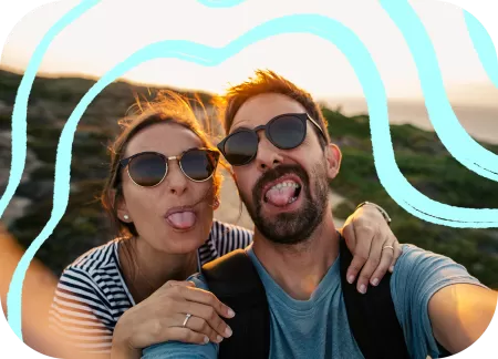 A couple is taking a goofy selfie out in nature.