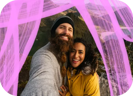 An interracial couple is taking a selfie in the mountains.
