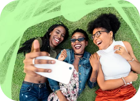 Three friends are lying on the grass and taking a selfie.