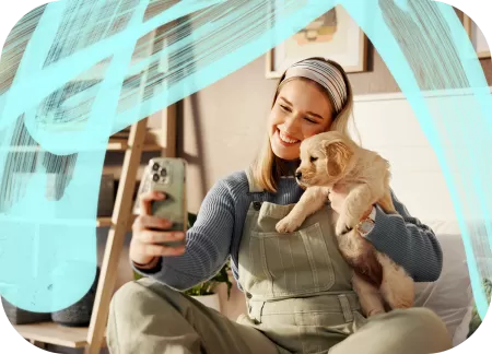 A young woman is sitting at home and taking a selfie with her puppy.